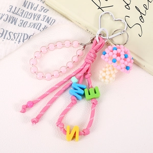 Detail of pink handmade beaded mushroom charm with letters on a woven cord