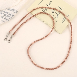 Close-up of rose gold mesh chain with lobster clasps on elegant fabric background