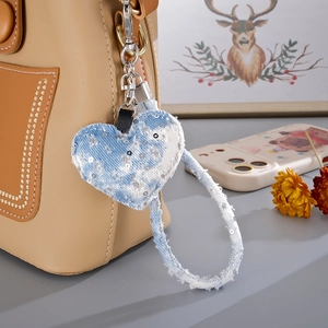 Close-up of heart denim charm with silver sequins and metallic lobster clasp on a bag