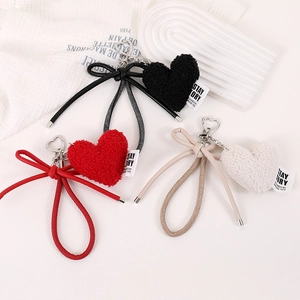 Three plush heart bag charms with bows in black, red and cream white with silver clips