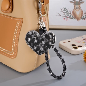 Close-up of distressed denim heart pendant with silver sequins on a leather bag