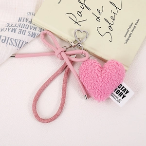 Close-up of pink plush heart keychain with a leather bow and shiny metal clasp