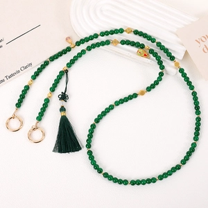 Detail of green beaded phone strap with gold hollow beads and silk tassel