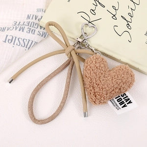 Close-up of brown plush heart charm with leather bow and heart-shaped metal clasp