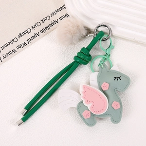 Handmade unicorn bag charm with plush ball and green leather strap in a premium design