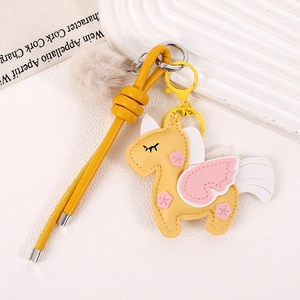 Detail of yellow unicorn leather keychain with pink wings and fluffy pompom charm