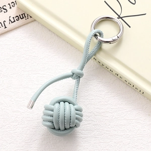 Close-up of light blue hand-woven PU leather ball keychain with silver spring buckle