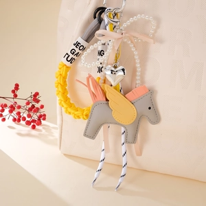 Cute PU leather Pegasus charm with yellow wings and woven rope on a beige handbag