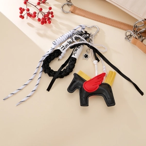 Close-up of handmade leather flying horse charm with colorful fringe and woven rope strap