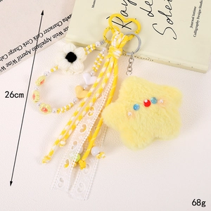 Detail of yellow plush star pendant with heart beads, knitted flower and lace ribbon charm