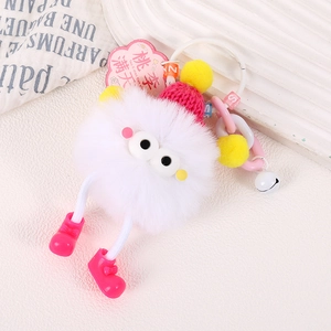Détail d'un porte-clés monstre en peluche blanche avec bonnet rouge et perles colorées