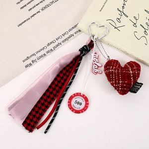 Detail of red houndstooth heart charm and ribbon on metallic carabiner keychain