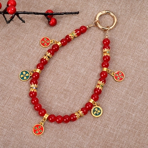 Detail of Chinese style red beaded phone charm with golden floral enamel pendants