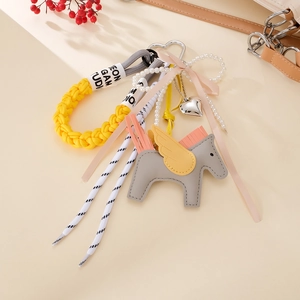 Close-up of a creative grey leather horse charm with yellow wings and pearl strap