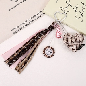 Detail of houndstooth woven tassel with heart plush and ribbon accessory on vintage books