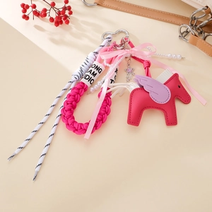 Detail of a pink leather flying horse keychain with woven rope and pearl bead charms