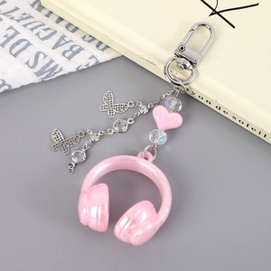 Macro detail of a pink music headphone keychain with silver butterfly charms and beads