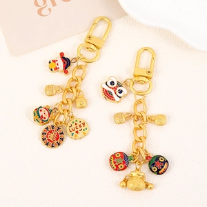 Golden Chinese lucky gourd keychain with lion dance and fortune bag charms on beige background
