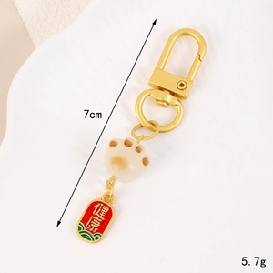 Cat paw keychain charm with gold hook and red Health tag on a white tray