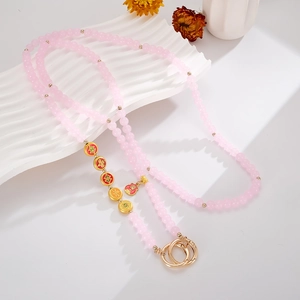 Detail der rosa Perlenkette mit goldenem Fu-Anhänger und Metallverschluss