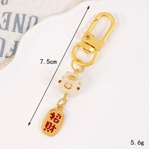 Vue détaillée du porte-clés chat porte-bonheur avec pendentif doré sur plaque blanche