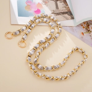 Detailed view of light gold metal chain woven with grey and white plush ribbon strap