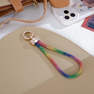 Dettaglio del cinturino da polso con strass arcobaleno, fiocco dorato e chiusura in metallo