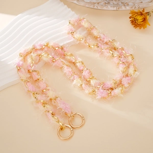 Pink and cream woven plush metal chain strap with dual gold rings on a warm background