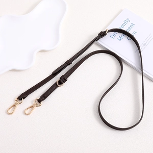 Detail view of dark brown lychee leather bag strap with adjustable gold buckle and hooks