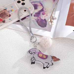 Detail of grey plush horse charm with purple Good Luck embroidery and silver wrist strap