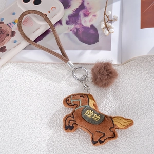 Detailed view of plush horse charm with Success embroidery and soft pompom accessory