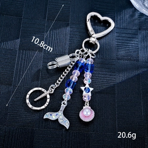 Star and mermaid tail pearl phone charm with pink shell and heart clasp on black background