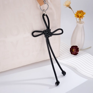 Detail of hand-woven black leather knot bag charm with metallic ring hook for phone or backpack