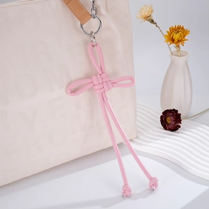 Detail of pink hand-woven leather Chinese knot charm on white perforated tote bag