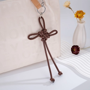 Detail of handcrafted brown PU leather woven knot bag charm with long tassels and gold ring