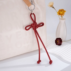 Detail of red hand-woven leather Chinese knot pendant hanging on a white luxury handbag