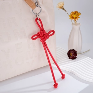 Detailed view of red PU leather Chinese knot pendant with silver ring on a white bag