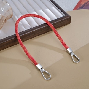 Dettaglio del cinturino intrecciato rosso in pelle con moschettoni in metallo lucido