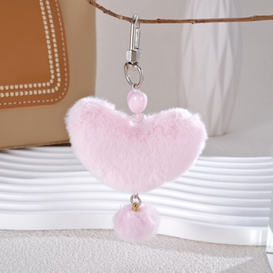Detail of soft pink heart-shaped plush keychain with silver lobster clasp and fuzzy pompom