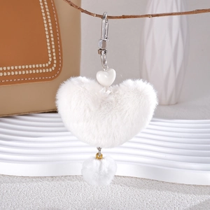 Close-up of white plush heart-shaped bag charm with silver carabiner and soft fur texture
