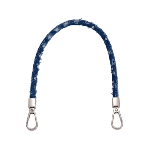 Détail d'une bandoulière tressée en denim bleu avec paillettes et mousquetons métalliques