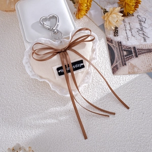 Close-up of heart-shaped plush pendant with lace trim and bow on vintage postcard