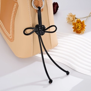 Detail of leather bag charm featuring hand-woven knot and premium stitching details