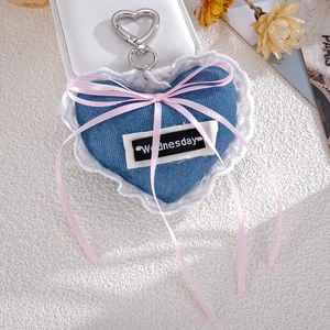 Detail of blue denim heart charm with white lace, pink bow, and silver heart clasp