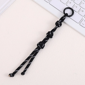 Detail of hand-woven black reflective nylon paracord bag charm with metal buckle