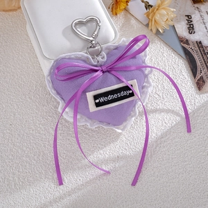 Detail of purple plush heart keychain with white lace edge and Wednesday ribbon label
