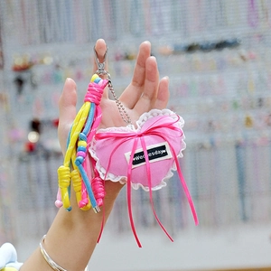 Pink heart plush keychain with white lace trim and colorful braided tassels on metal chain
