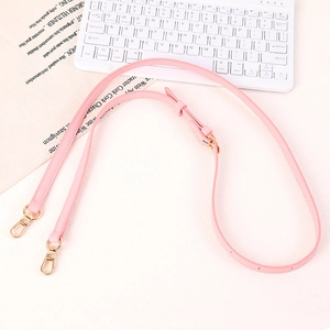 Detail of adjustable pink faux leather bag strap with golden metal swivel hooks and buckles
