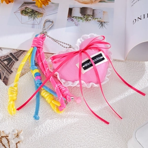 Detail of pink denim heart keychain with white lace, ribbon bow and colorful braided rope