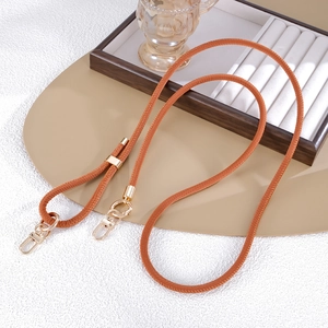 Detail of adjustable orange woven crossbody strap with polished gold metal hardware